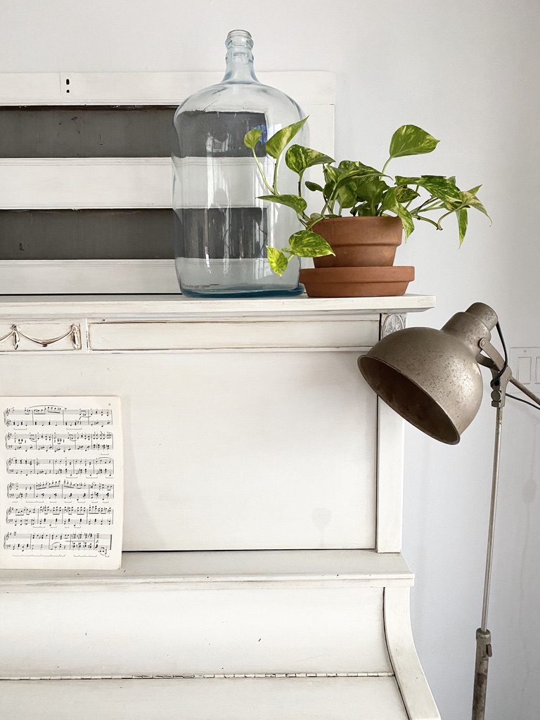 A vintage piano styled with summer inspired decor and a vintage floor lamp