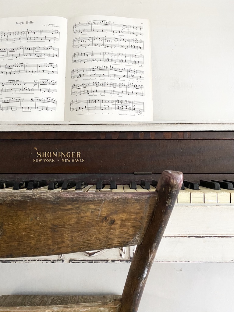 An antique piano painted white with vintage sheet music