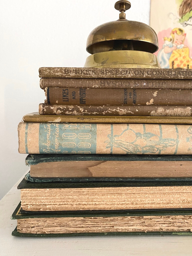 Vintage book bundles stacked with a brass bell on top as back to school decor