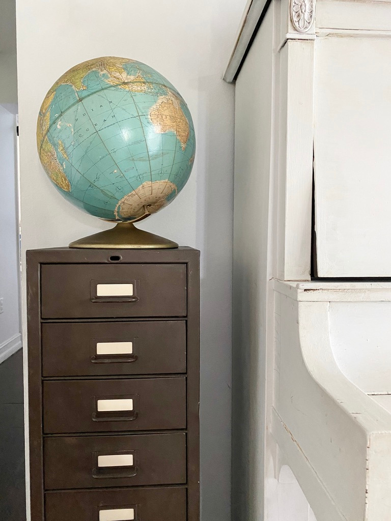 A metal nine drawer cabinet with a vintage globe on top provides back to school storage
