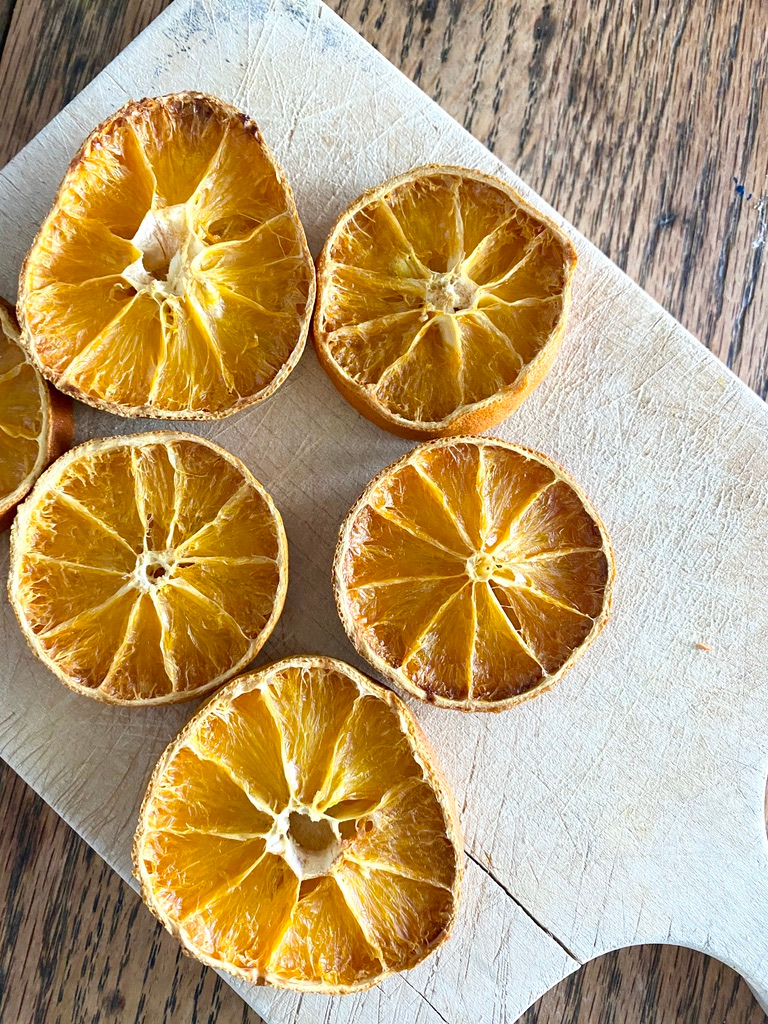 Dried oranges on a wooden cutting board on a dining table
