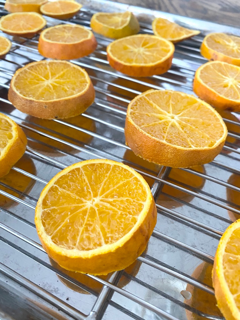 Fresh orange slices on a cooling rack over a baking sheet