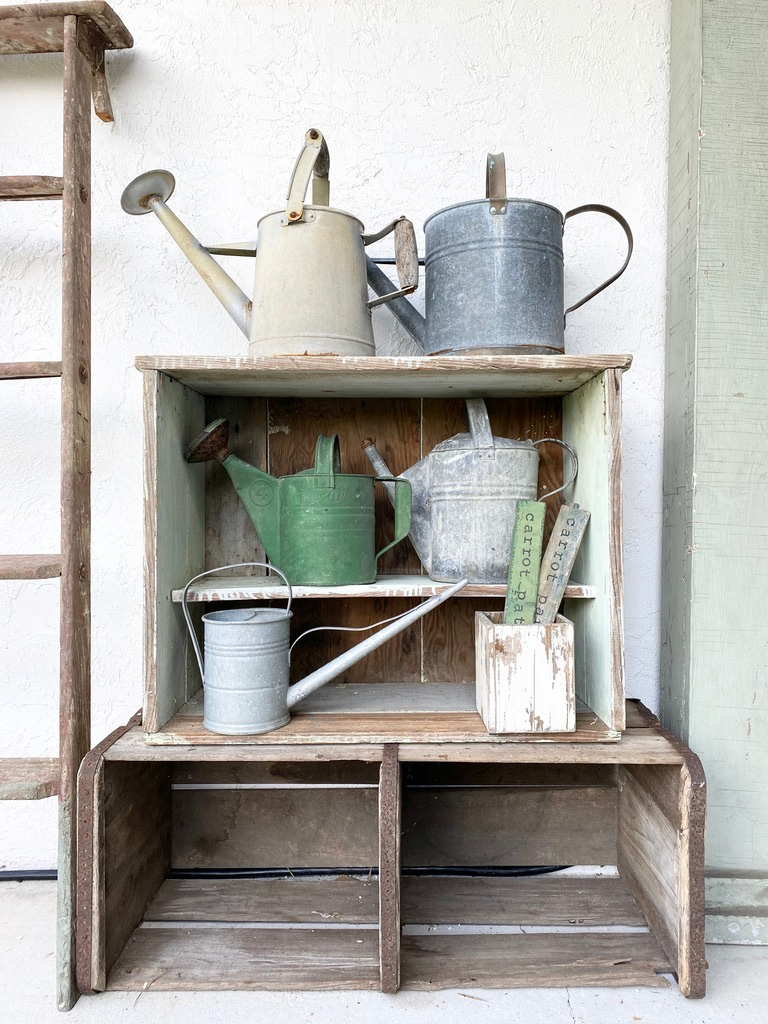 vintage watering cans stacked on crates