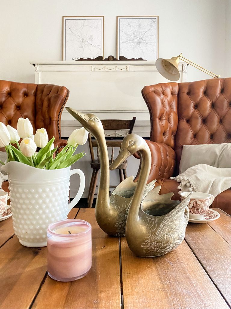 Vintage brass swans on a coffee table with a vase of tulips